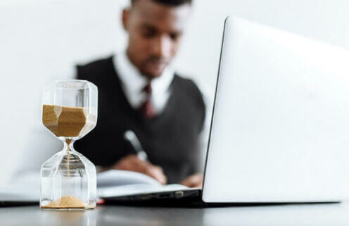 statute of limitations on dog bites shown with hourglass in front of man sitting at desk writing in front of computer